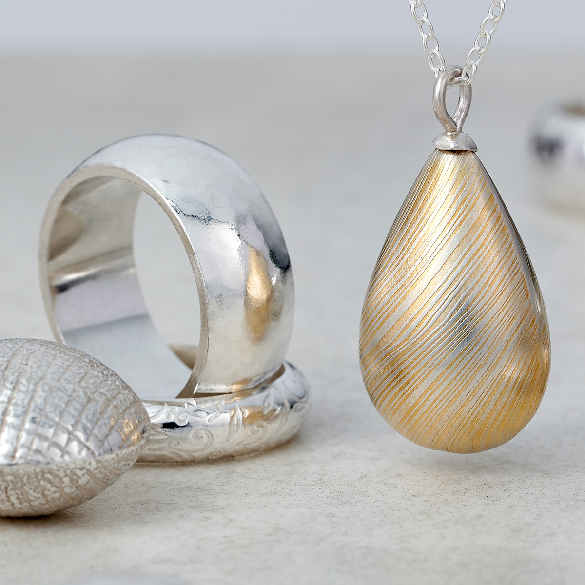 Hollow form ring and pendant course A Hollow form silver ring and pendant on a light stone background