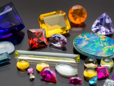 An assortment of different gemstones in many shapes and sizes and colours scattered on a black perspex background