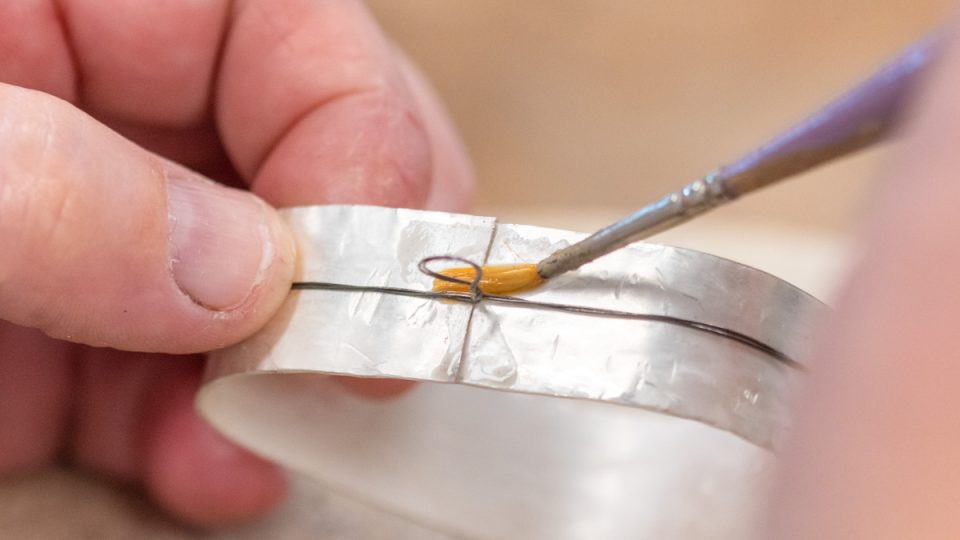Applying flux to a silver sheet with a brush