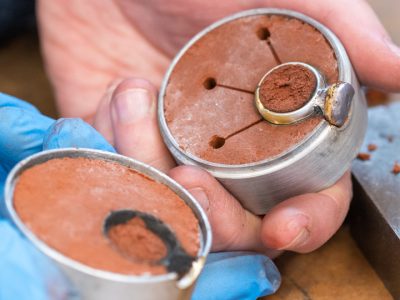 Sand cast silver ring in a flask full of sand being opened