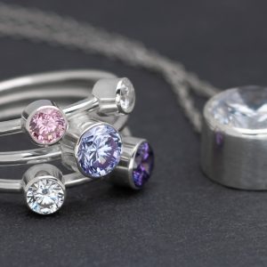 Silver ring with a number of round faceted stones and a silver setting also with a faceted stone on a slate background