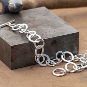 Silver hammered chain on a steel flat plate and texturing hammer