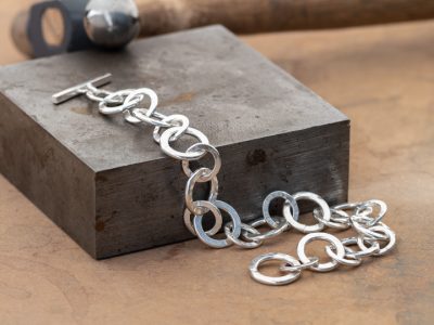 Silver hammered chain on a steel flat plate and texturing hammer